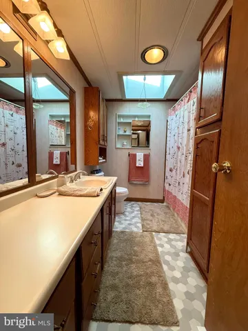 a hall with open cabinet and a large mirror