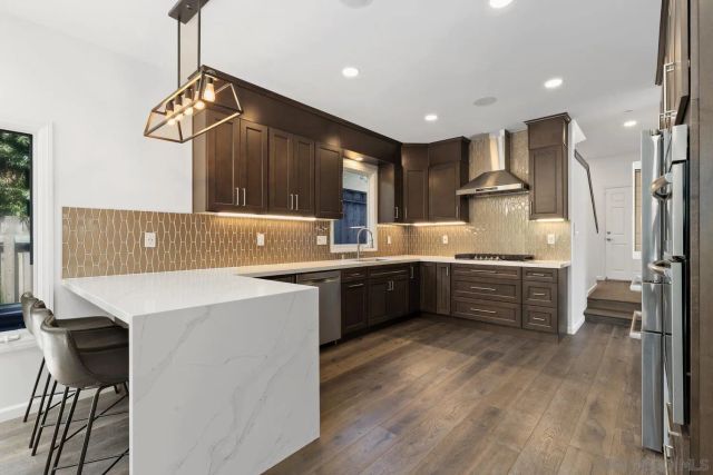 a kitchen with kitchen island wooden cabinets a sink a stove a refrigerator and a stove