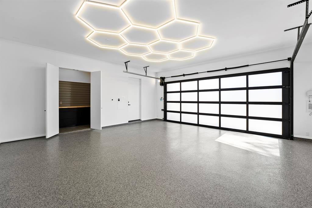 9457 Waterview Road Dallas, TX 75218 - Photo 18 of 25 Spacious garage with hexagonal ceiling lighting and a glass-paneled roll-up door