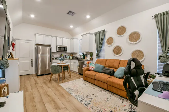 a living room with stainless steel appliances furniture and a view of kitchen