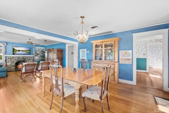 a dining room with wooden floor a chandelier a glass table and chairs