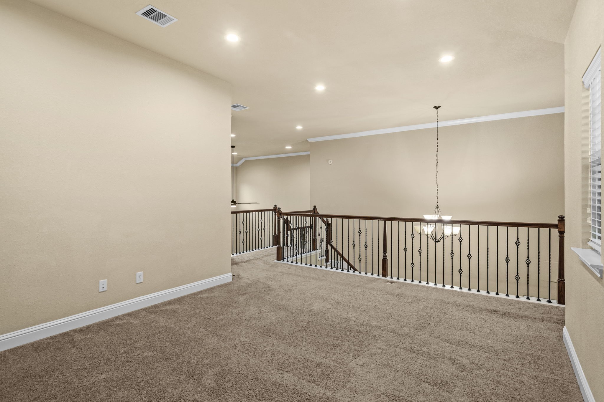 14215 Spindle Arbor Road Cypress, TX 77429 - Photo 20 of 47 This photo showcases an upstairs landing area with plush carpet, neutral walls, and recessed lighting. A decorative railing overlooks the staircase, and a hanging light fixture adds elegance. Ideal for a cozy sitting area or workspace.