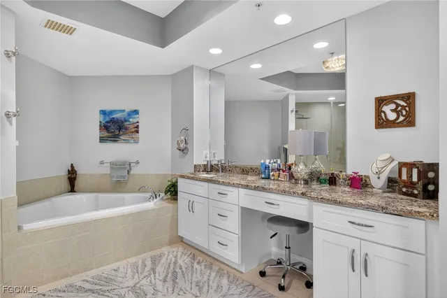 a bathroom with a tub sink double vanity and mirror