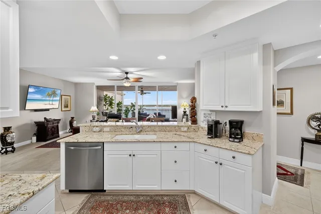 a kitchen with stainless steel appliances granite countertop a sink dishwasher stove and white cabinets