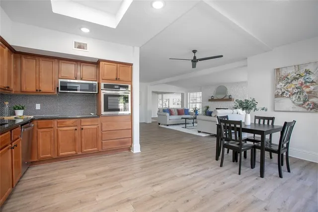 a kitchen with stainless steel appliances granite countertop a kitchen island hardwood floor sink stove dining table and chairs