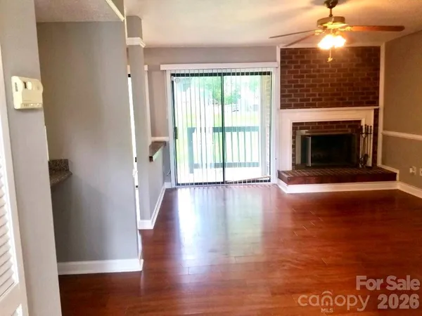 a view of a livingroom with wooden floor a fireplace and window