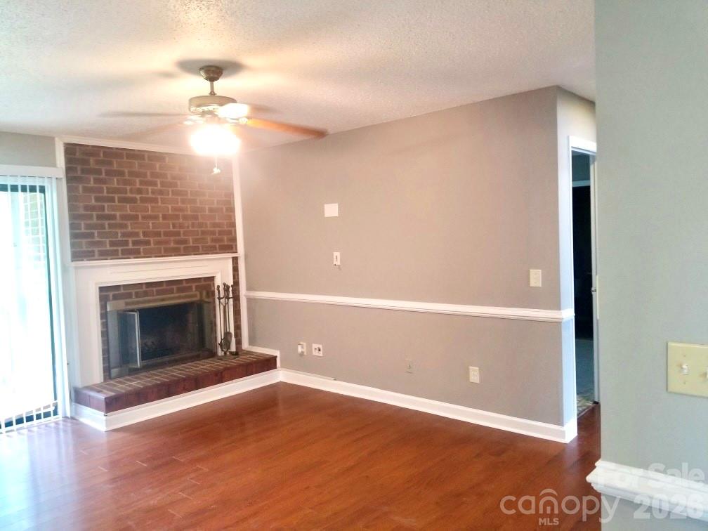 11027 Harrowfield Road Charlotte, NC 28226 - Photo 6 of 15 an empty room with wooden floor fireplace and windows