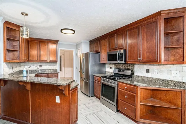 a kitchen with stainless steel appliances granite countertop wooden cabinets a stove top oven a sink and dishwasher