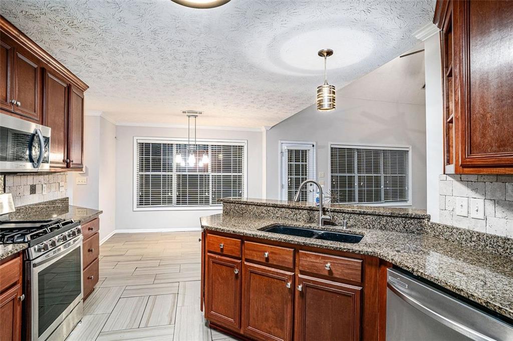 3205 Haleys Way Southeast Conyers, GA 30013 - Photo 8 of 25 a kitchen with stainless steel appliances granite countertop a sink and a stove