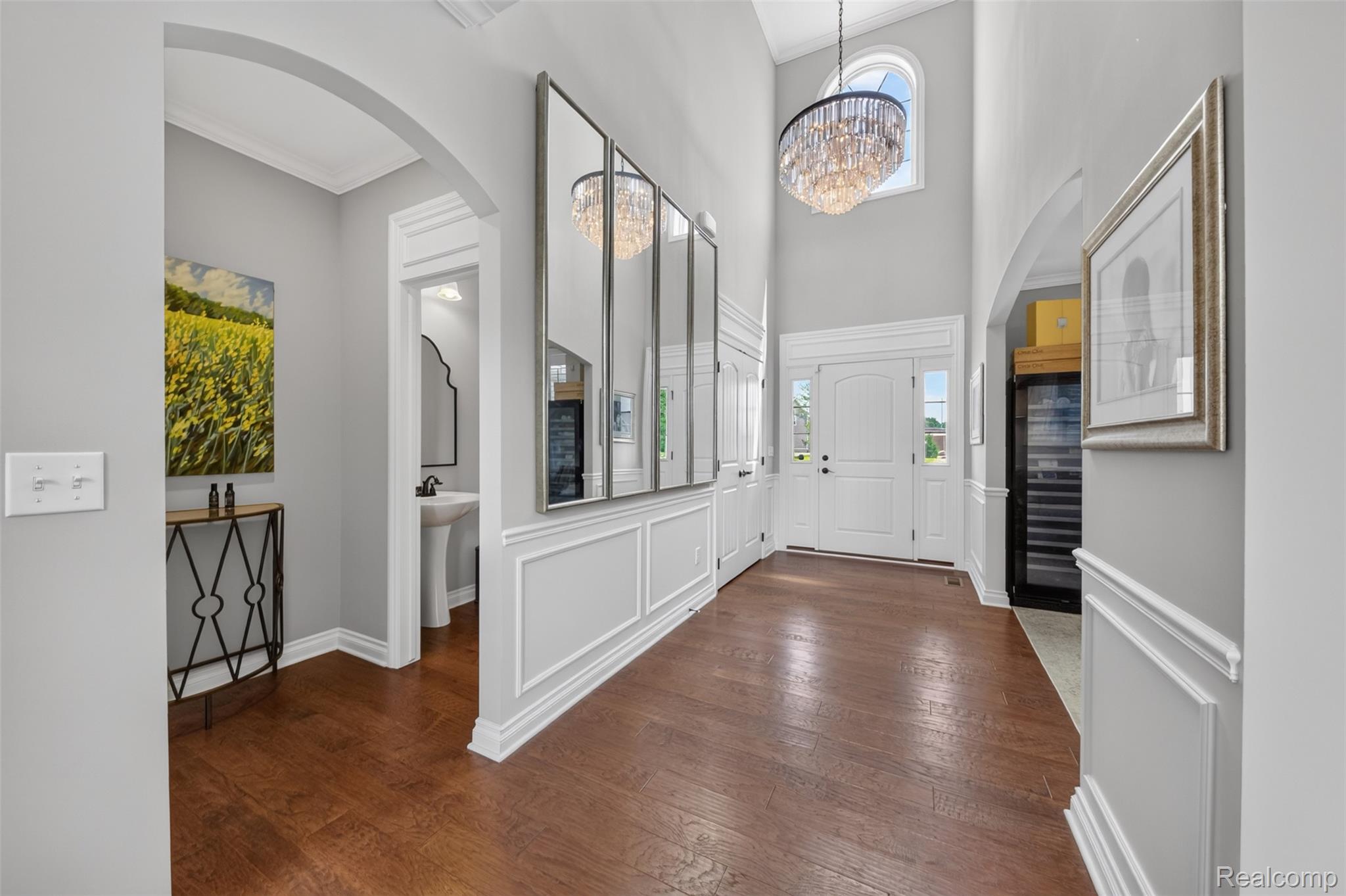 2531 Walnut View Drive Howell, MI 48855 - Photo 6 of 34 Grand foyer featuring a double-door entry, hardwood-finish flooring, a two-story ceiling, a large chandelier, and extensive wall paneling