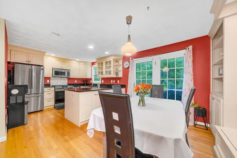 a kitchen with stainless steel appliances kitchen island granite countertop a refrigerator a stove top oven a sink dishwasher and white cabinets with wooden floor