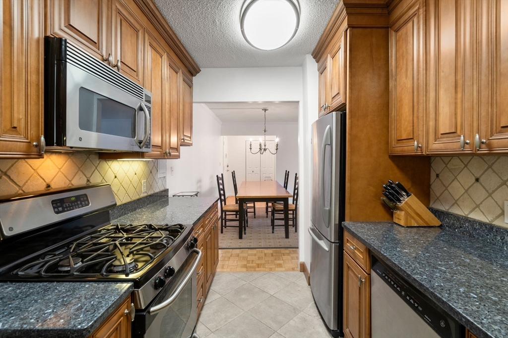 33 Pond Avenue, Unit 405 Brookline, MA 02445 - Photo 3 of 17 a kitchen with wooden cabinets and a stove top oven