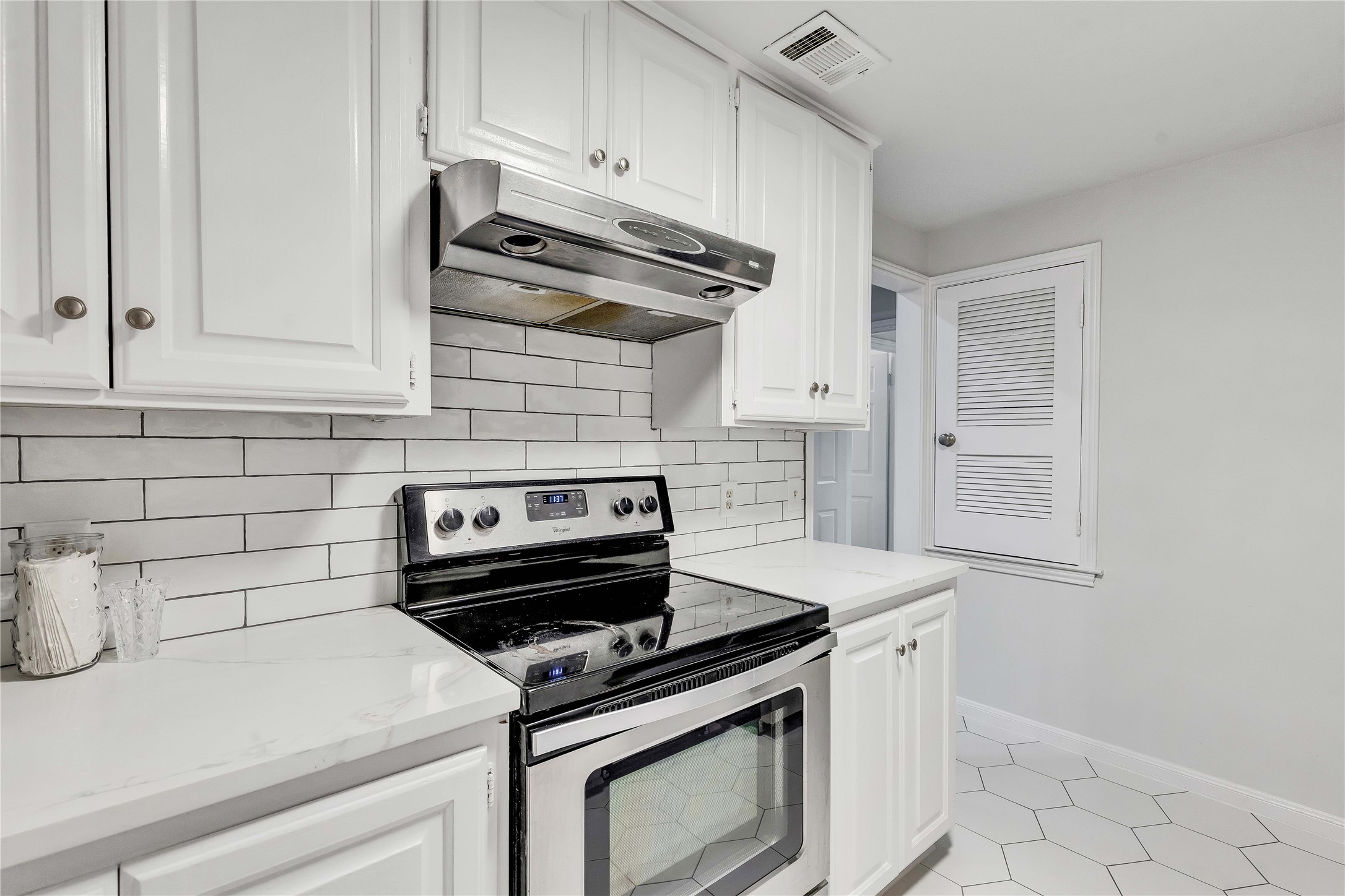 2529 Rio Grande Street, Unit 56 Austin, TX 78705 - Photo 4 of 16 Kitchen featuring visible vents, under cabinet range hood, decorative backsplash, stainless steel electric range oven, and white cabinets