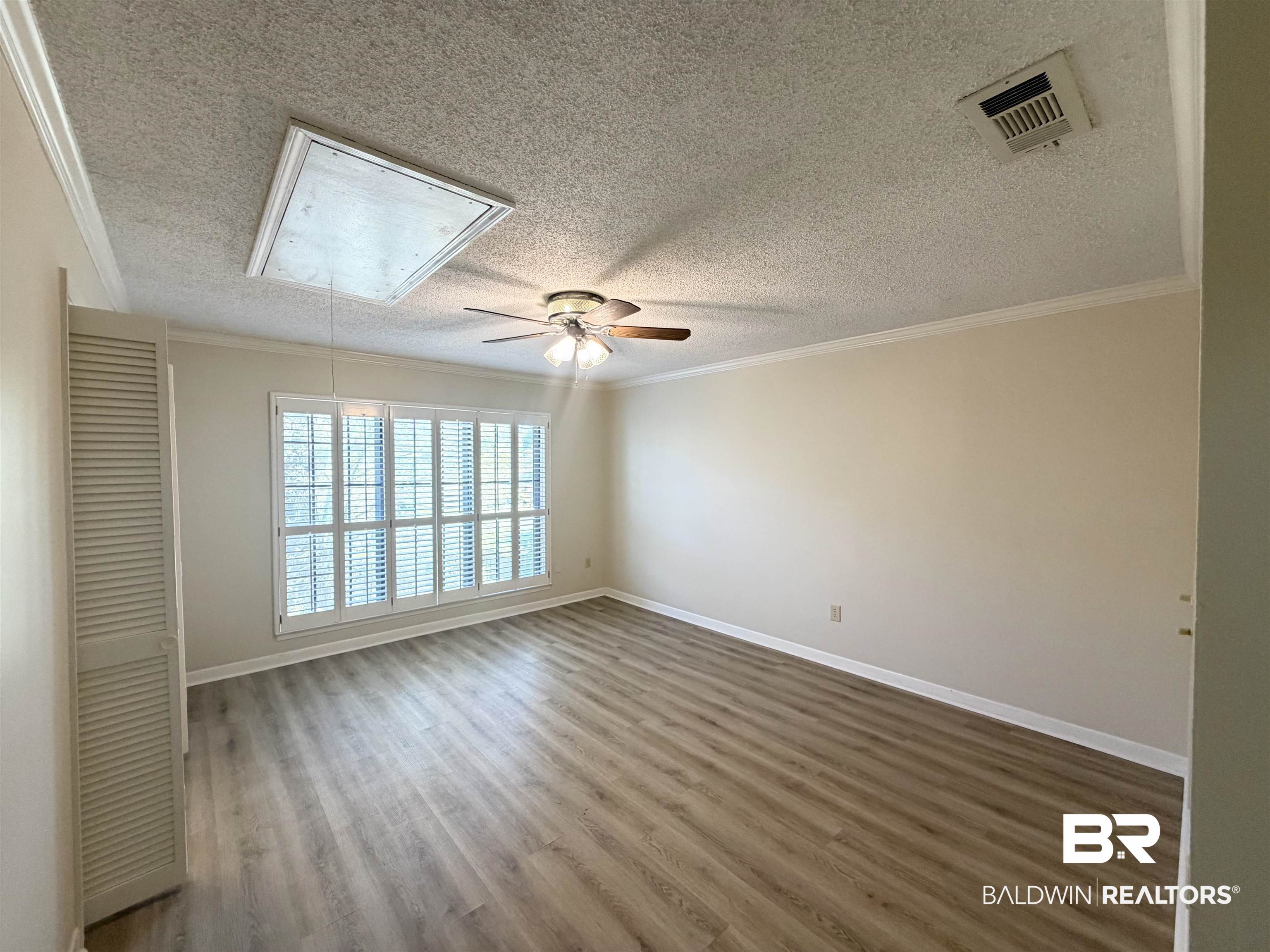 2901 Grant Street, Unit 902 Mobile, AL 36606 - Photo 31 of 35 Spare room featuring wood finished floors, a ceiling fan, a textured ceiling, and crown molding