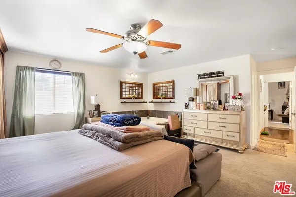 a bedroom with a large bed and ceiling fan
