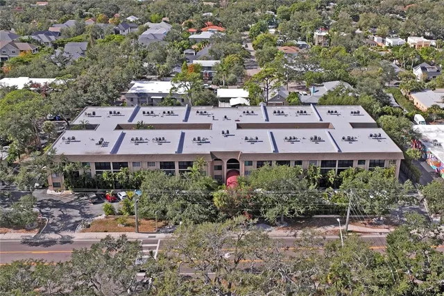 an aerial view of a house with a yard and large tree