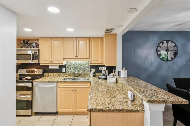 a kitchen with kitchen island granite countertop a stove a sink and a refrigerator