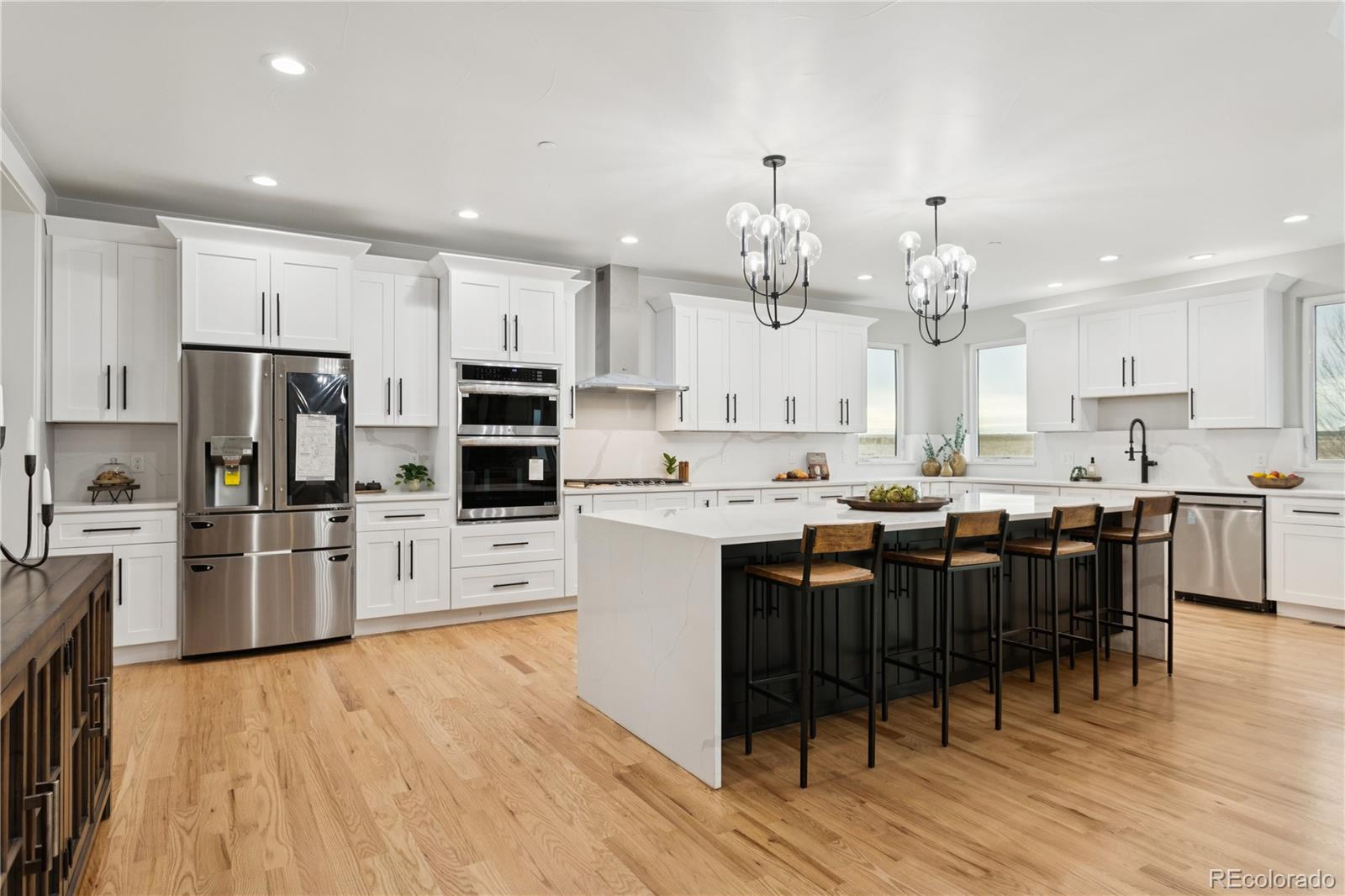 12550 Imboden Road Hudson, CO 80642 - Photo 12 of 50 a kitchen with stainless steel appliances kitchen island granite countertop a large refrigerator a stove a sink a dining table and chairs with wooden floor