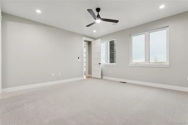 an empty room with ceiling fan and windows