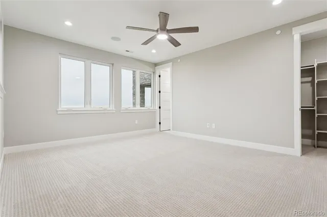 an empty room with windows and ceiling fan