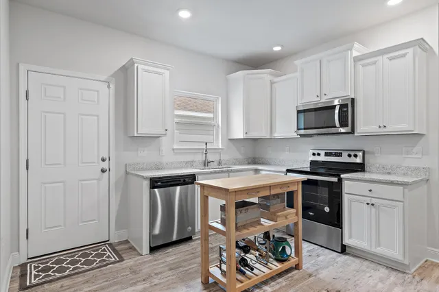 a kitchen with stainless steel appliances granite countertop a refrigerator a stove a sink a dining table and chairs with wooden floor