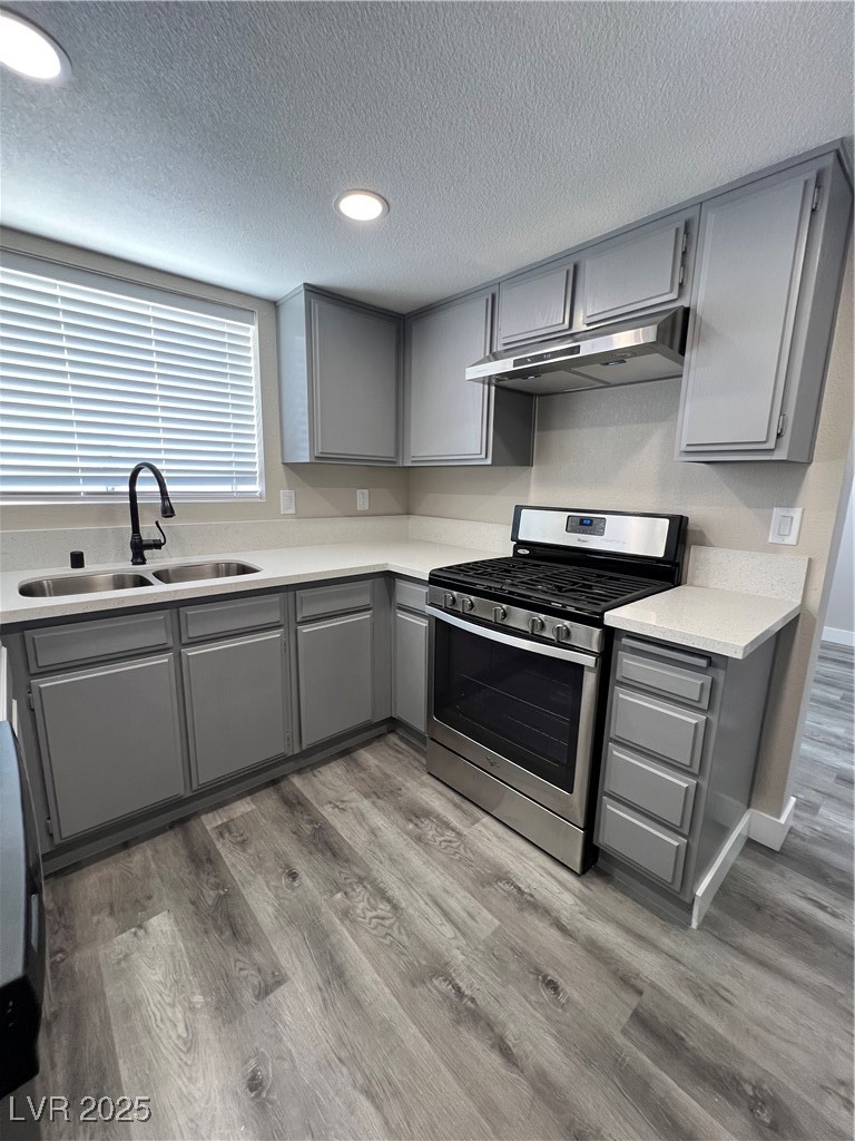 3238 Canyon Terrace Drive Laughlin, NV 89029 - Photo 14 of 41 Kitchen with gray cabinets, gas range, a textured ceiling, ventilation hood, and light wood-style floors