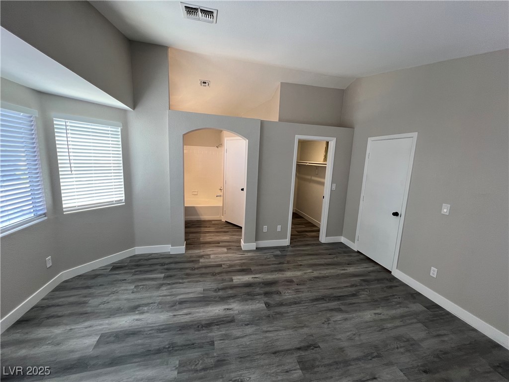 3238 Canyon Terrace Drive Laughlin, NV 89029 - Photo 28 of 41 Unfurnished bedroom with arched walkways, a walk in closet, connected bathroom, dark wood-style flooring, and vaulted ceiling