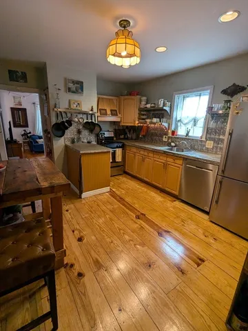 a kitchen with stainless steel appliances kitchen island granite countertop a stove and white cabinets