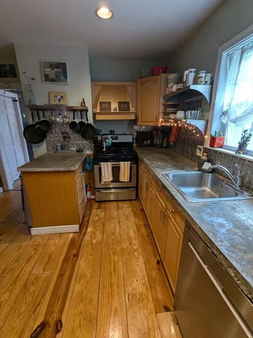 a kitchen with stainless steel appliances granite countertop a sink a stove counter space and cabinets