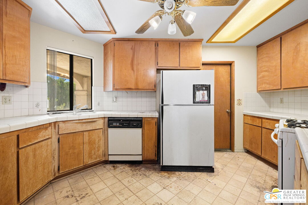 68600 Risueno Road Cathedral City, CA 92234 - Photo 13 of 30 a kitchen with stainless steel appliances granite countertop a refrigerator a sink and white cabinets