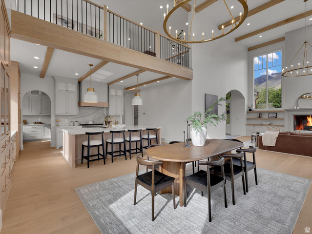 13216 Telemark Lane Draper, UT 84020 - Photo 5 of 41 Dining area featuring light wood-style flooring, arched walkways, a chandelier, a mountain view, and a high ceiling
