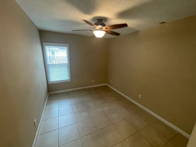 an empty room with a ceiling fan and carpet