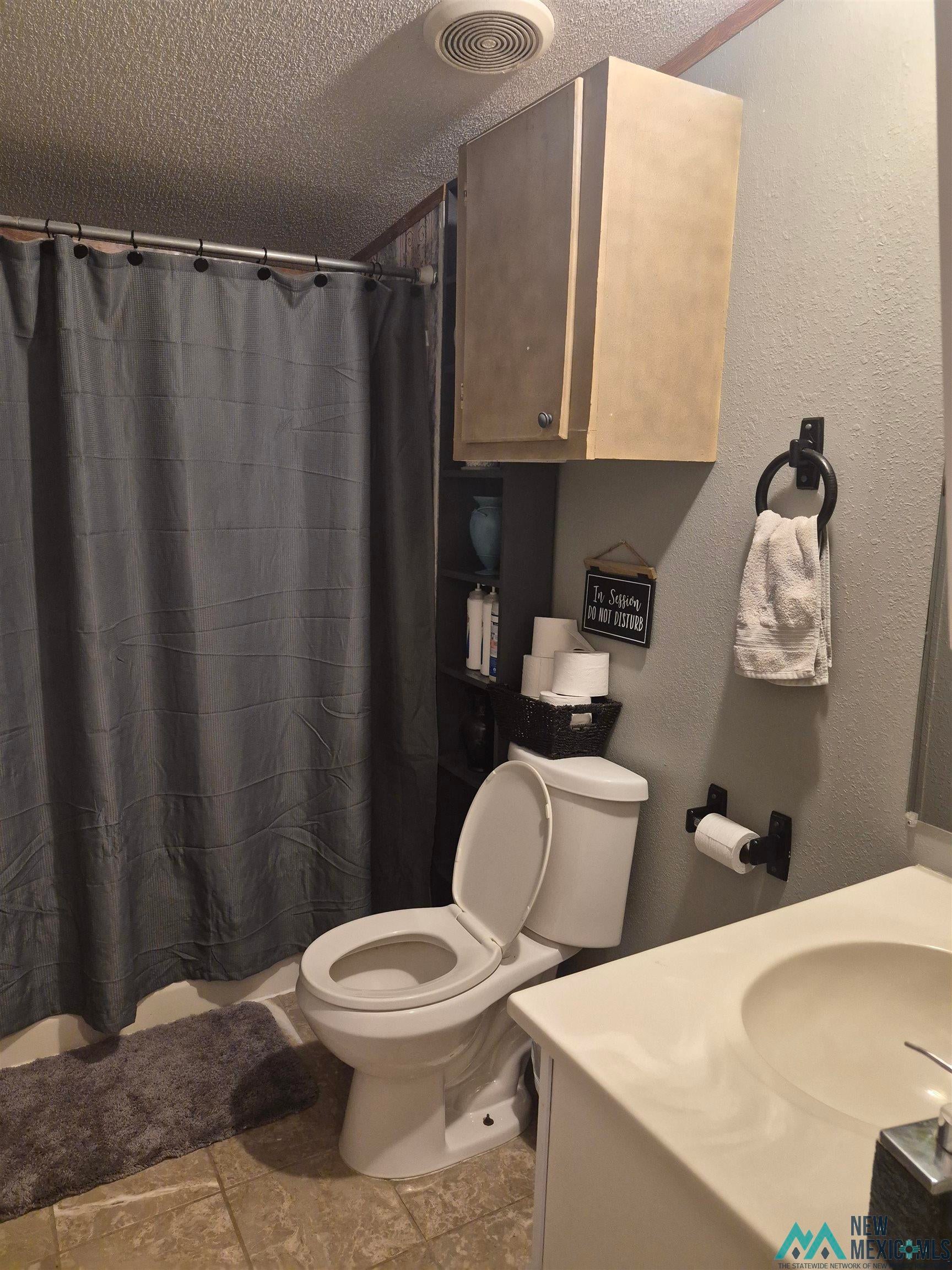751 South Roosevelt Rd R 1/2 Portales, NM 88130 - Photo 12 of 21 Bathroom featuring vanity, a textured wall, a textured ceiling, and shower / tub combo with curtain