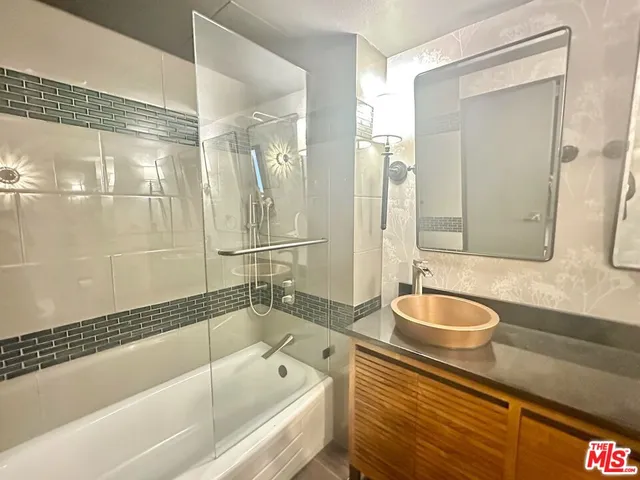 a bathroom with a granite countertop tub sink shower and mirror