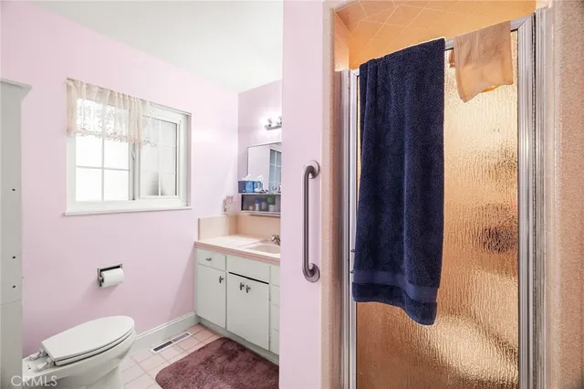 a bathroom with a sink a toilet a window and shower