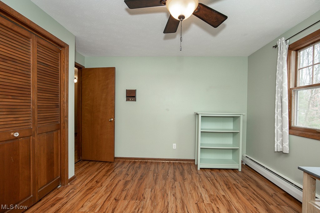 2969 Center Road Avon, OH 44011 - Photo 22 of 33 Unfurnished bedroom with light wood-type flooring, a closet, ceiling fan, and a baseboard heating unit