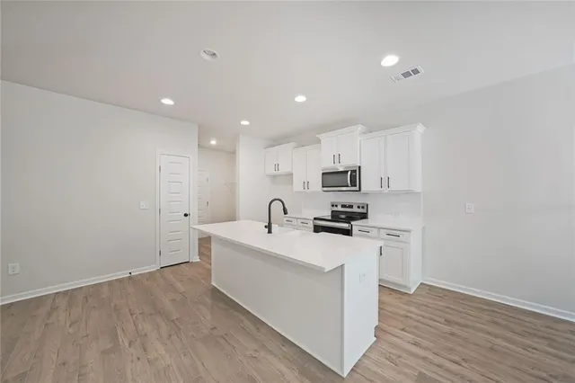 a kitchen with a sink a stove cabinets and wooden floor