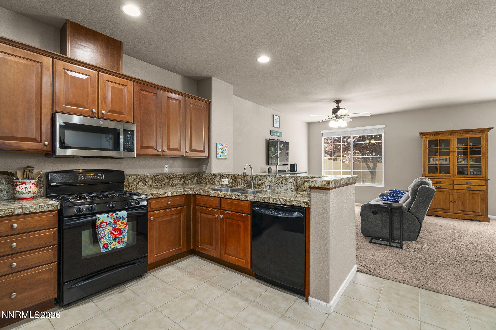 11041 Colton Drive Reno, NV 89521 - Photo 4 of 28 a kitchen with stainless steel appliances granite countertop a stove top oven a sink dishwasher a dining table and chairs with wooden floor