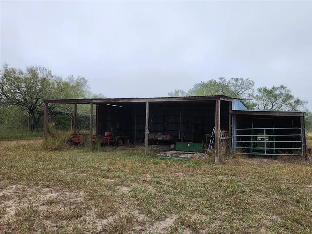 a view of a dry yard with trees in the background