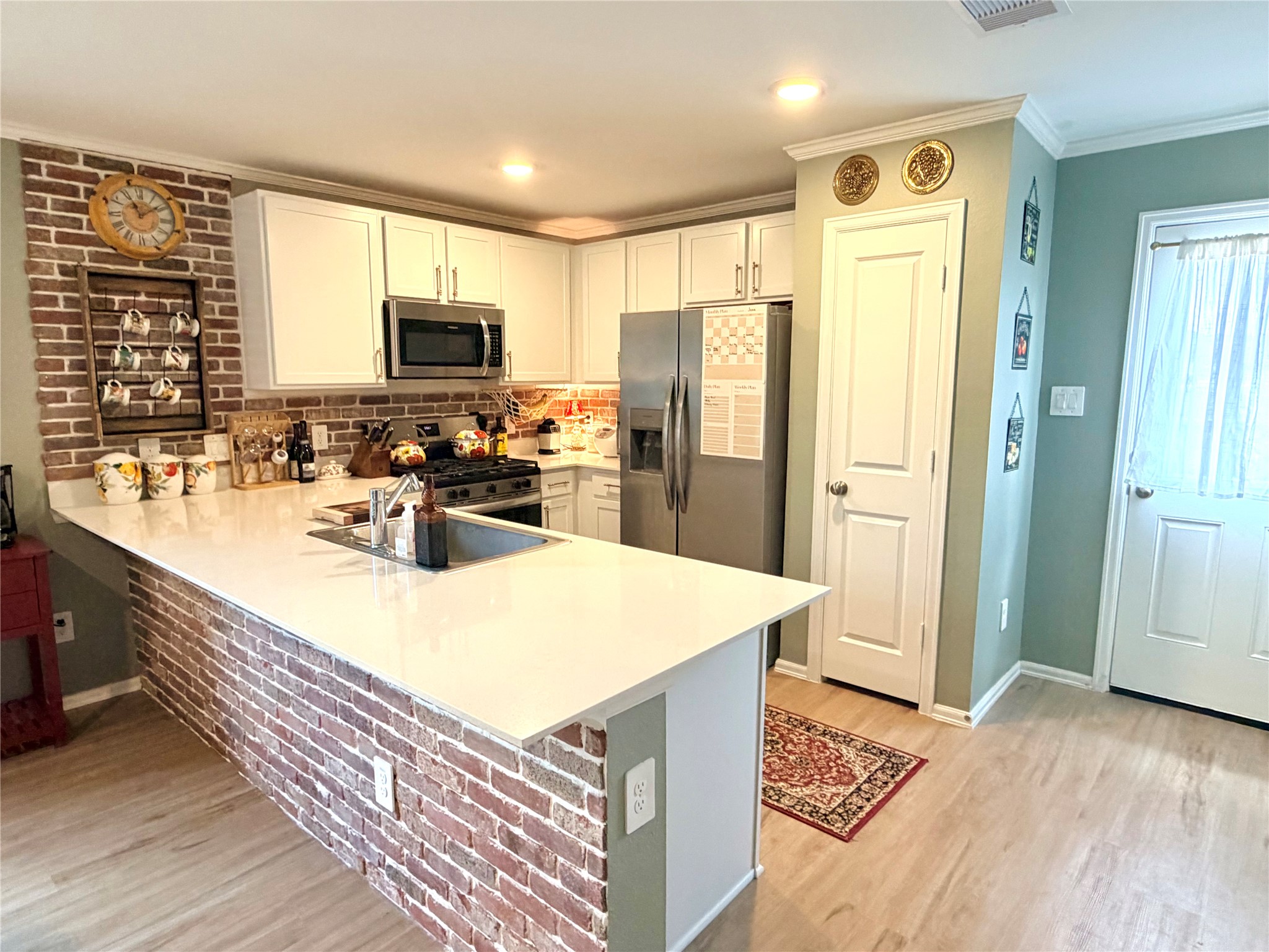 532 Flower Reed Court Magnolia, TX 77354 - Photo 14 of 43 This Chef's kitchen features a modern design with a brick accent wall, white cabinetry, and stainless steel appliances. The space is bright, with recessed lighting and a large countertop, perfect for cooking and entertaining!