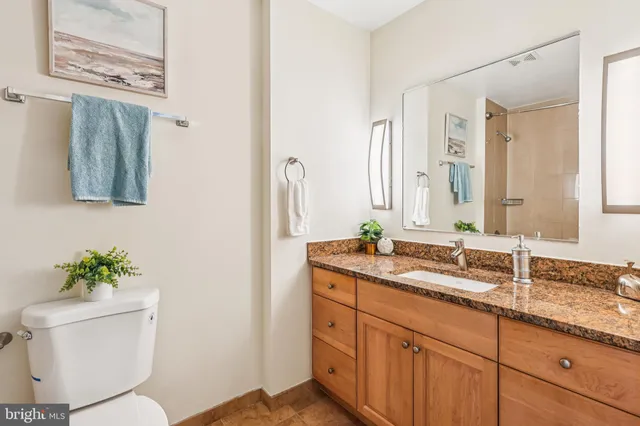 a bathroom with a granite countertop toilet sink and mirror