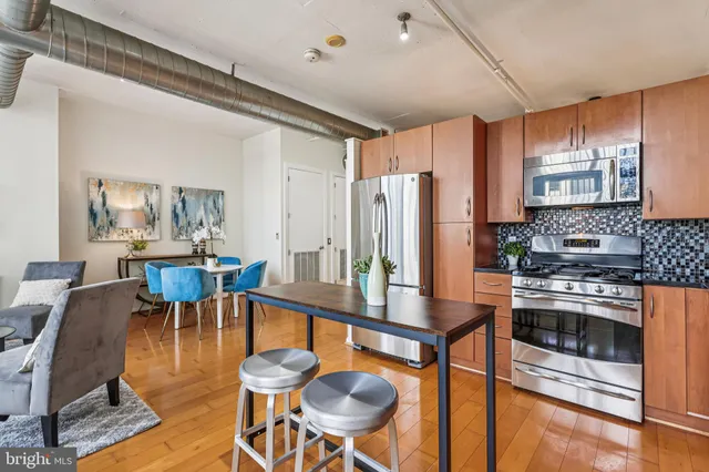 a kitchen with stainless steel appliances kitchen island granite countertop a table chairs stove and refrigerator