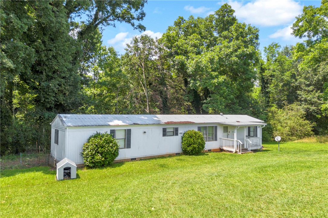 150 Newberry Road Walhalla, SC 29691 - Photo 2 of 47 A quaint residence nestled amidst verdant trees, featuring a welcoming front porch and expansive lawn.