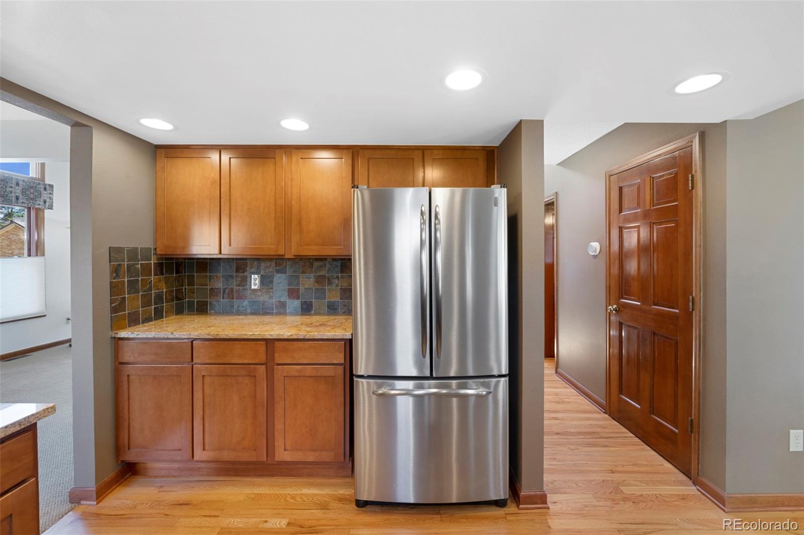 7975 Sweet Water Road Lone Tree, CO 80124 - Photo 14 of 43 a kitchen with stainless steel appliances a refrigerator and wooden floor