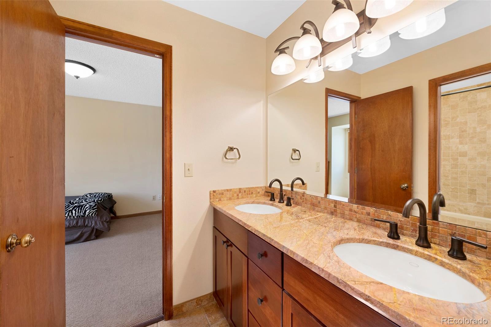 7975 Sweet Water Road Lone Tree, CO 80124 - Photo 31 of 43 a bathroom with a granite countertop sink a large mirror and vanity