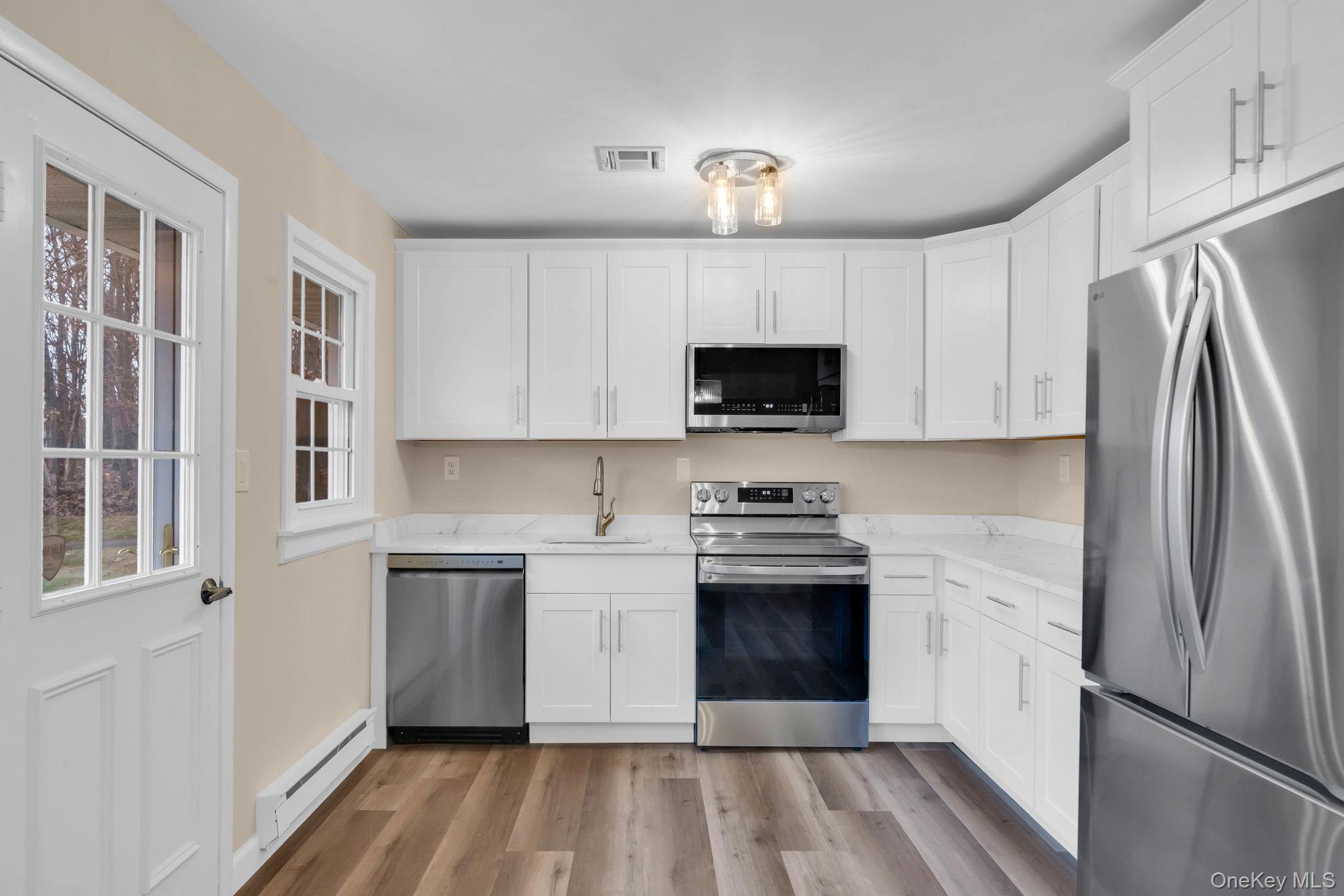 380 Woodbridge Drive, Unit D Ridge, NY 11961 - Photo 2 of 25 a kitchen with stainless steel appliances granite countertop a refrigerator sink and stove