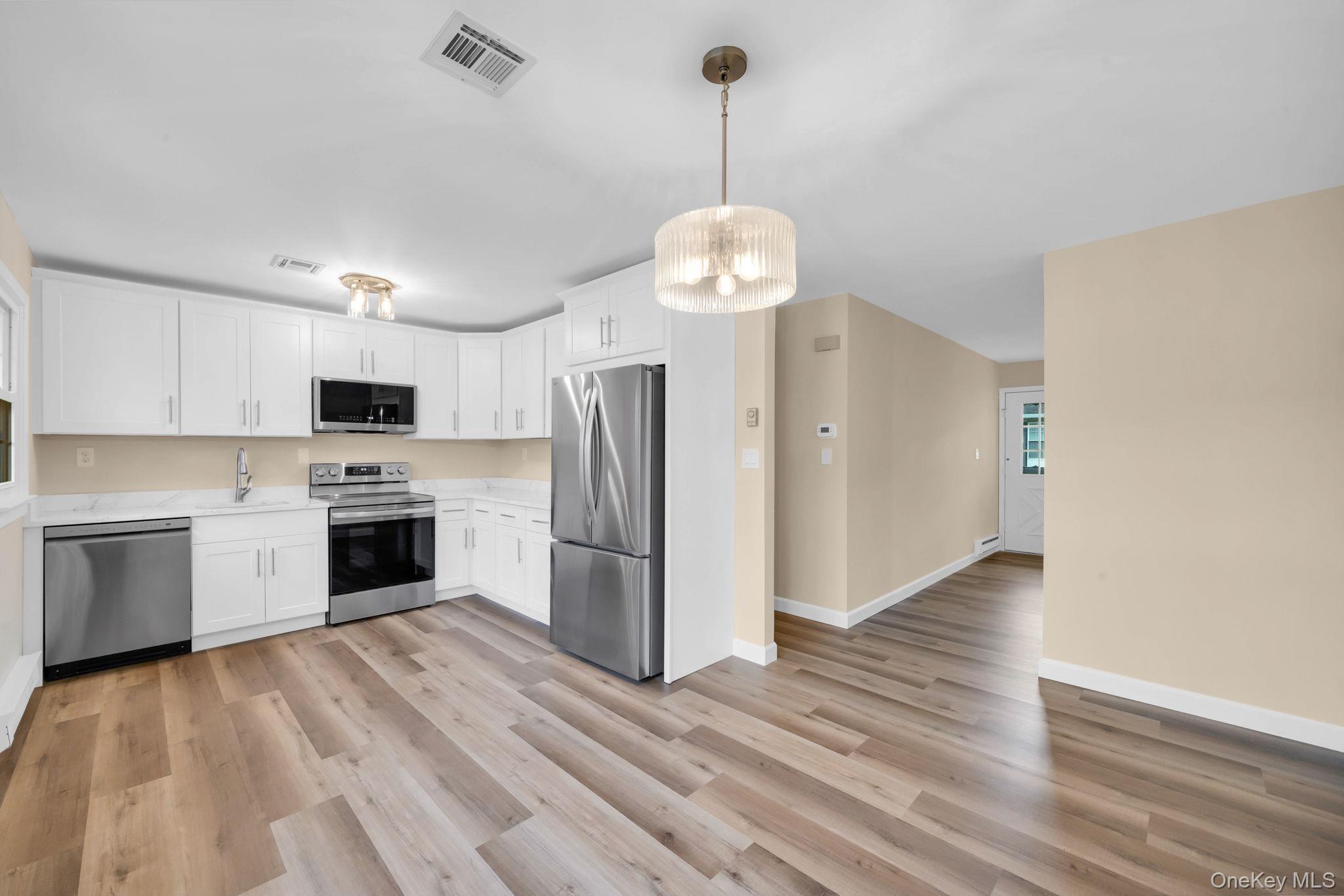 380 Woodbridge Drive, Unit D Ridge, NY 11961 - Photo 3 of 25 a kitchen with stainless steel appliances a stove a refrigerator and a sink