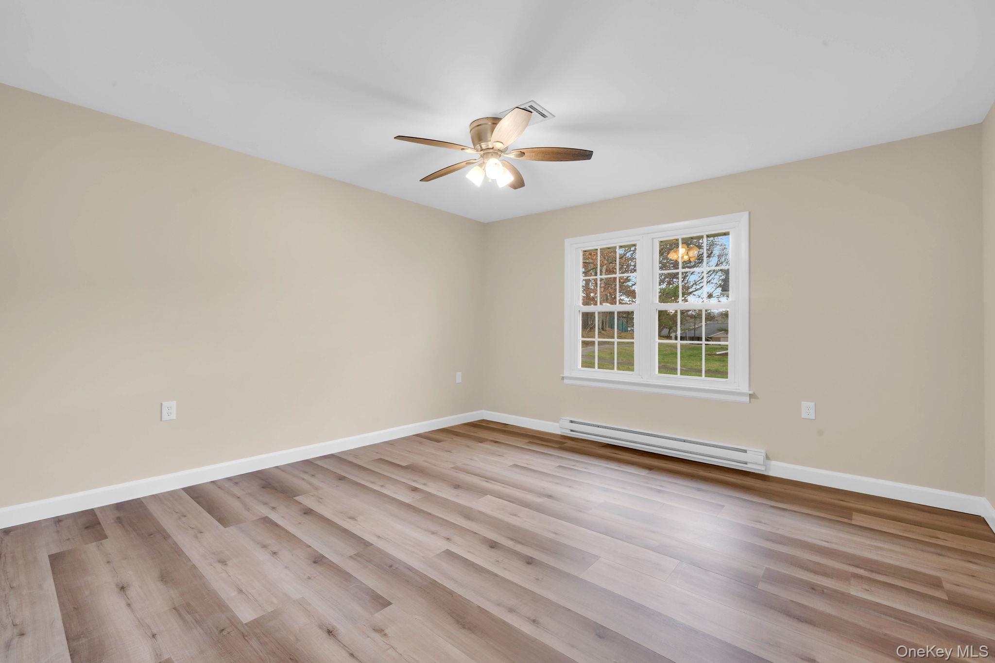 380 Woodbridge Drive, Unit D Ridge, NY 11961 - Photo 10 of 25 wooden floor in an empty room with a window