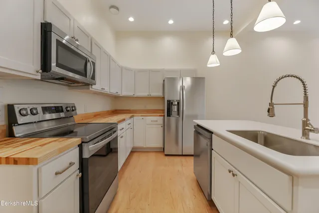 a kitchen with stainless steel appliances granite countertop a sink a stove and a refrigerator