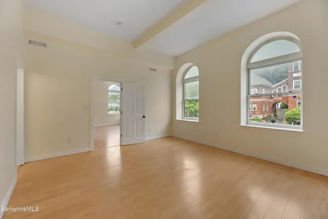 an empty room with windows and wooden floor